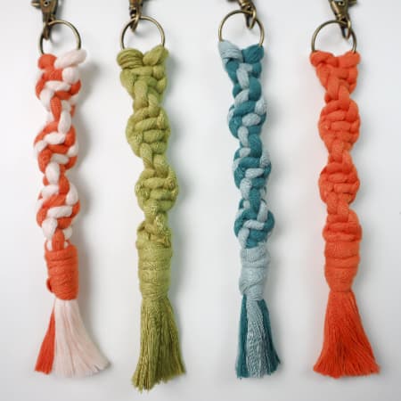 Easy macrame keychain tutorial with four colorful knotted tassel keychains and wrapped cord ends.